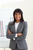 Ethnic businesswoman with folded arms in front of a board 