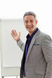 Cheerful mature businessman pointing at a board 