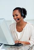 Cheerful businesswoman with headset on working at a computer