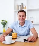 Attractive man reading a newspaper while having breakfast