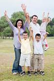 Happy family on outdoors  enjoying by raising hands