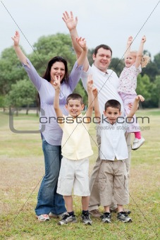 Happy family on outdoors  enjoying by raising hands