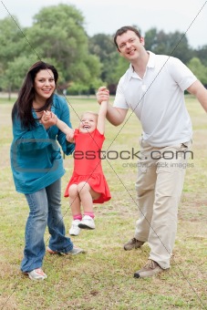 Lovely couples playing with their happy daughter at the park 