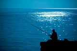 silhouette man fishing in sea glittering
