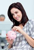 Delighted businesswoman saving money in a piggy-bank