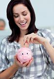 Cheerful businesswoman saving money in a piggy-bank 