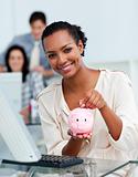 Smiling businesswoman saving money in a piggy-bank 