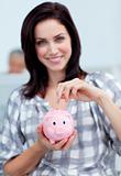 Charismatic businesswoman saving money in a piggy-bank