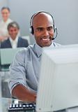 Smiling businessman with headset on working at a computer