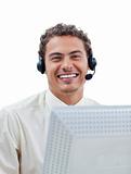 Positive businessman talking on headset at a computer