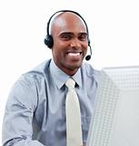 Happy businessman talking on headset at a computer