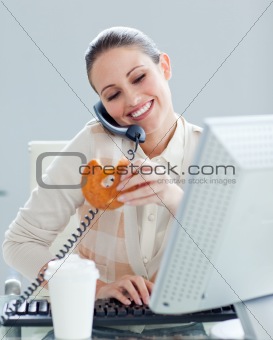 Confident businesswoman on phone eating a donnut