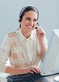 Assertive businesswoman with headset on working at a computer 