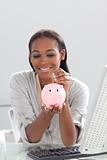Afro-american businesswoman saving money in a piggybank 