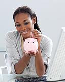 Assertive Afro-american businesswoman saving money in a piggyban