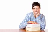 happy smiling male student sitting on desk with books
