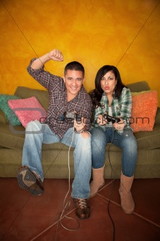 Attractive Hispanic Couple Playing a Video Game with Handheld Controllers