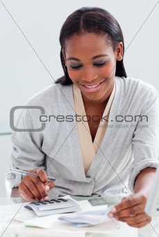 Smiling businesswoman using a calculator at her desk
