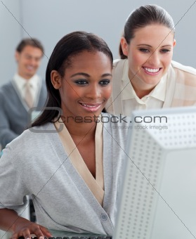 Charming businesswoman helping her colleague at a computer