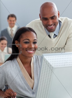 Confident businessman helping his colleague at a computer