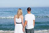 Enamored couple holding hands at the shore line 