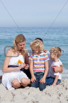 Attentive mother holding sunscreen at the beach 
