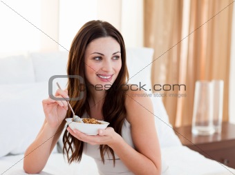 Pretty woman eating cereals sitting on bed