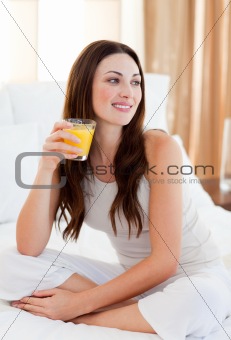Beautiful woman drinking orange juice on bed