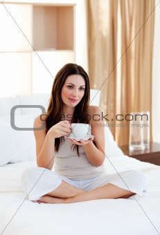 Attractive woman drinking coffee sitting on bed