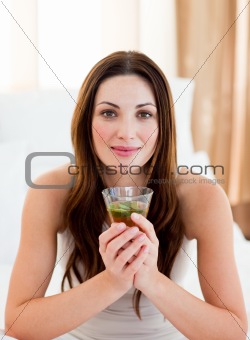 Young brunette woman drinking tea sitting on bed