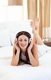 Brunette woman listening music lying on bed