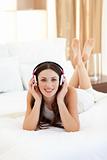 Pretty woman listening music lying on bed