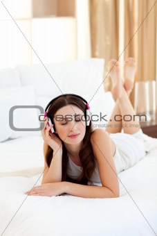 Relaxed woman listening music lying on bed