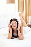 Positive woman listening music lying on bed