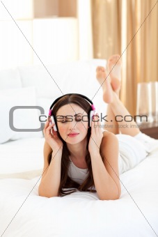 Positive woman listening music lying on bed