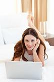 Smiling woman looking at a laptop lying on bed