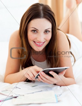 Young woman doing her accounts lying on bed