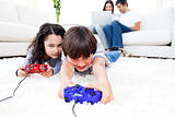 Excited children playing video games lying on the floor 