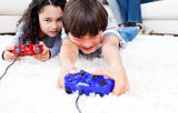 Jolly children playing video games lying on the floor 