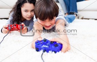 Jolly children playing video games lying on the floor 