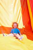 happy little boy enjoying a ride down the slide in amusement park
