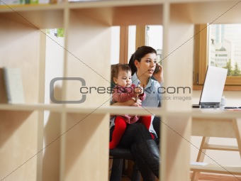 businesswoman on the phone, holding daughter