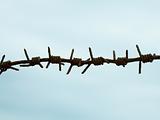 Ancient rusty barbed wire against sky