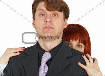 Young woman hides behind big shoulders of man