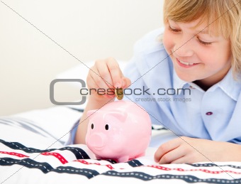 Cute boy putting a coin in a piggybank 