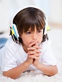 Pensive little boy listenning the music at home