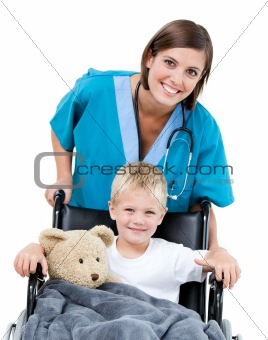 Nice female doctor carrying adorable little boy in the wheelchai
