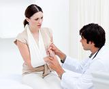 Young male doctor examining the female patient by taking her arm