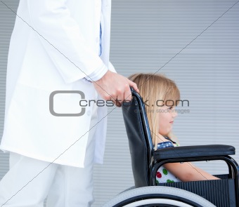 Smiling little girl sitting on the wheelchair supported by a doc