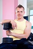portrait of a young man holding dumbbells in modern gym